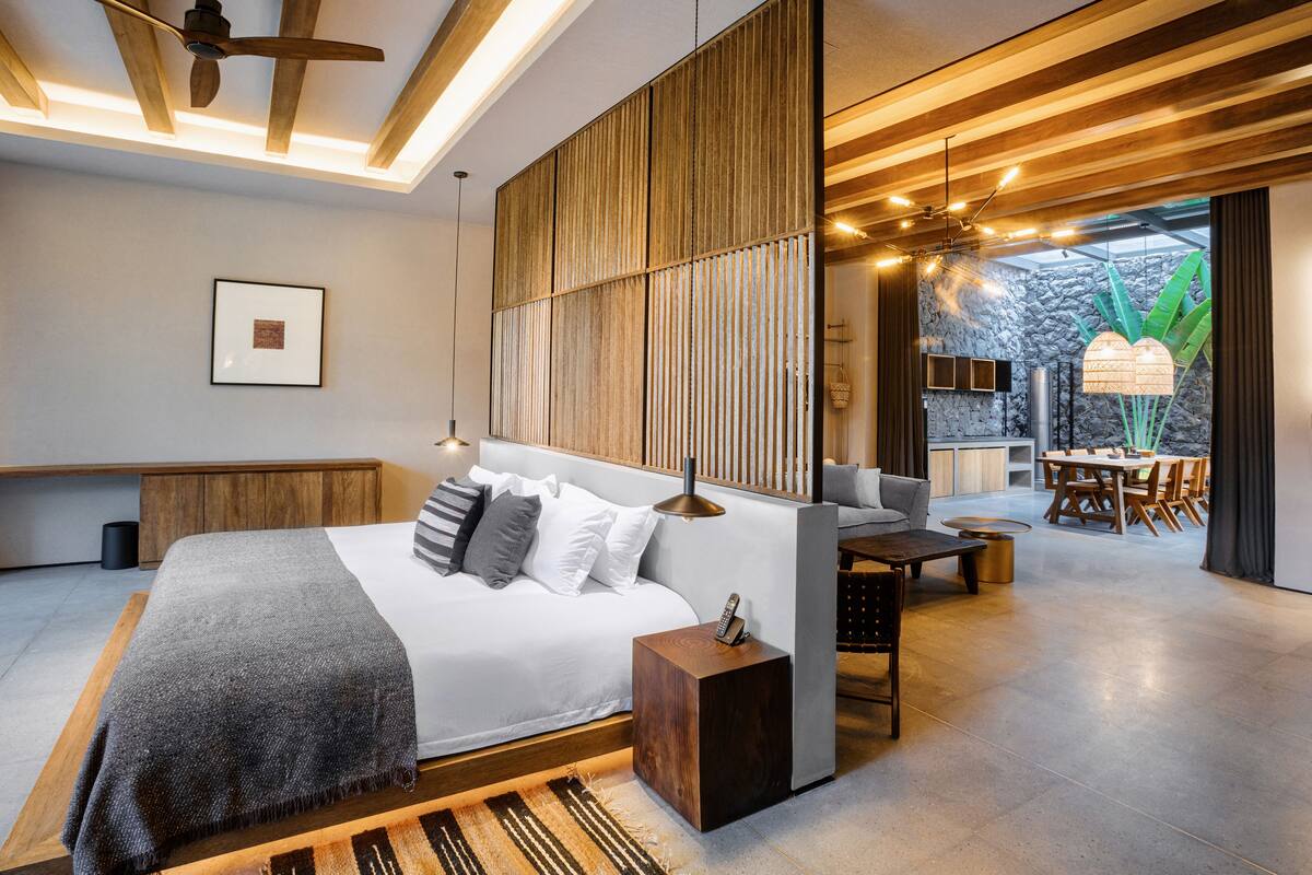 Un dormitorio moderno con una cama grande, una mesita de noche y vistas a un comedor.