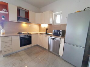 Enjoy cooking in this well-lit kitchen with a refrigerator, dishwasher, and microwave.