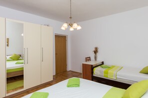 A bedroom with a bed, a wardrobe, a desk, and a chair.