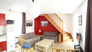 A living room with a sofa, a coffee table, a TV, and a staircase.
