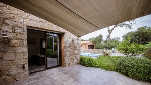 A stone exterior wall with a glass door leading to a patio area. - Modern villa with private pool and garden, in a secure estate (Porto-Vecchio)