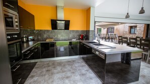 A modern kitchen with a central island, built-in appliances, and a bright yellow accent wall. - Modern villa with private pool and garden, in a secure estate (Porto-Vecchio)