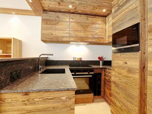 A modern kitchen with wooden cabinetry, granite countertops, and a Siemens microwave.