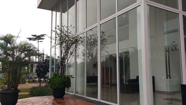 A modern building with large glass windows and a paved entrance area with potted plants. - Studio Room Apartment Aeropolis by Rusdi (Tangerang)