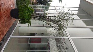 A modern building with large glass windows and a potted plant on the left. - Studio Room Apartment Aeropolis by Rusdi (Tangerang)