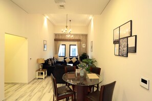 Relax in this stylish living area with a sofa, coffee table, and dining table, surrounded by framed artwork and a potted plant.