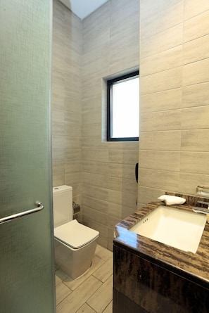 Bathroom features a toilet, sink, and light-colored tiles.
