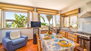 A dining area with a table set for two, a television, and a kitchen with a stove. - 3 bedroom awesome home in Menfi (Menfi)