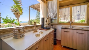 A kitchen with a view of the beach, wooden cabinets, a coffee machine, and a small island with decorative items. - 3 bedroom awesome home in Menfi (Menfi)