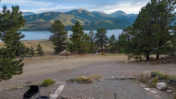 Ein Campingplatz mit Grill, Picknicktisch und schöner Aussicht auf Berge und einen See.