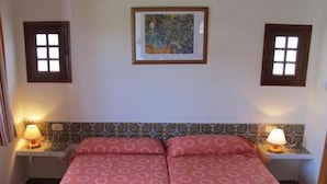 A bedroom with a double bed, two bedside lamps, a patterned headboard, and a framed artwork on the wall. - Son Bou Apartments (Alayor)