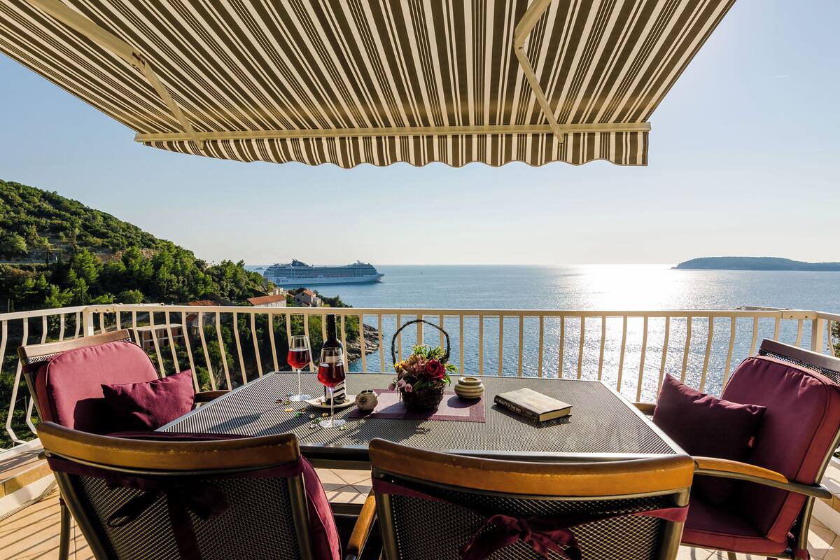 A terrace with a table, chairs, and a view of the sea.
