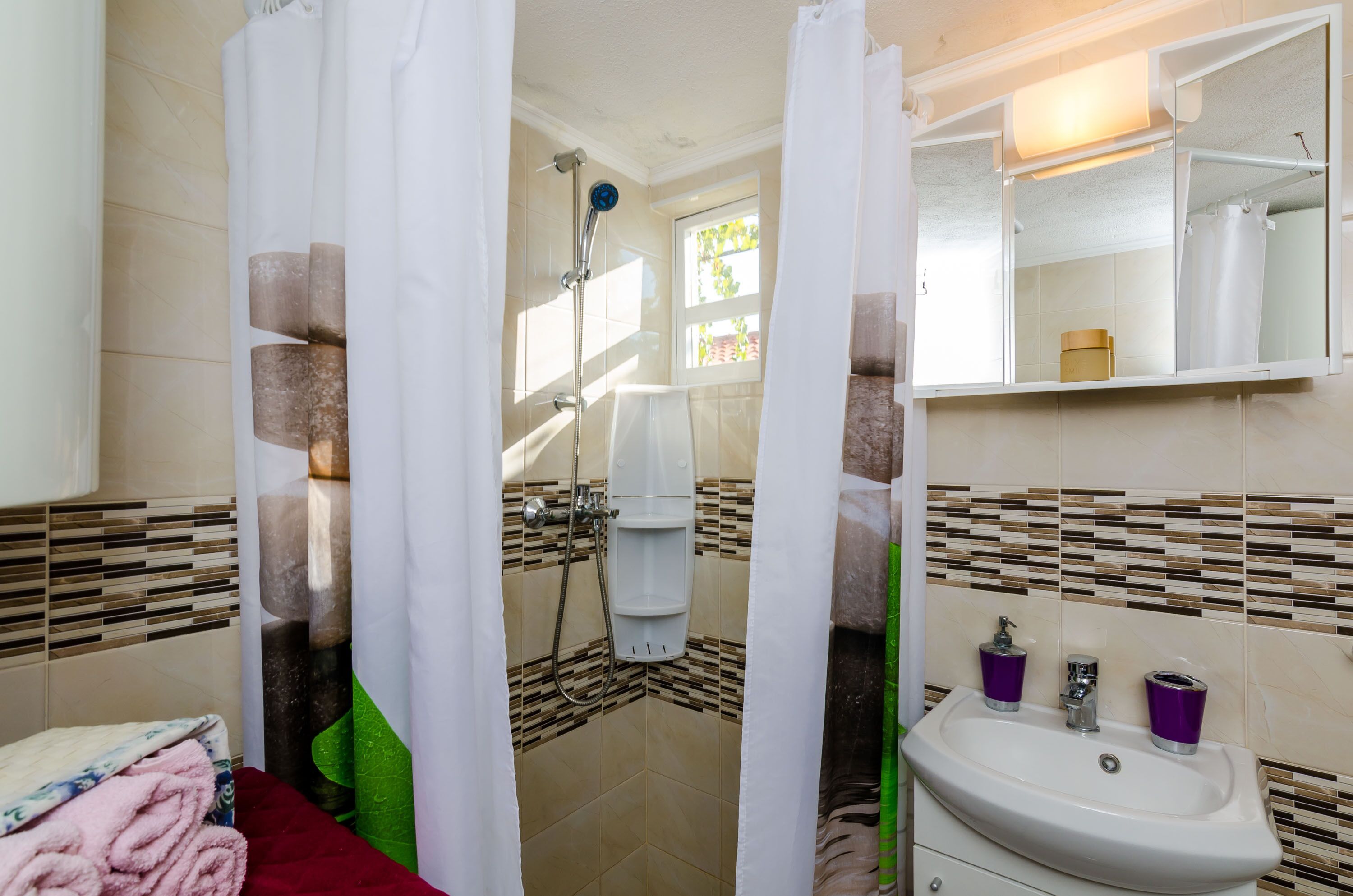 Un bagno con doccia, lavandino e specchio.