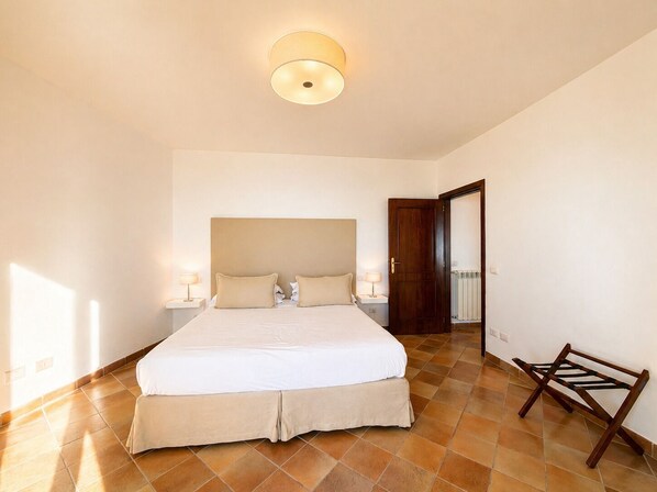 A bedroom with a large bed, two bedside tables, a wooden door, and a radiator.