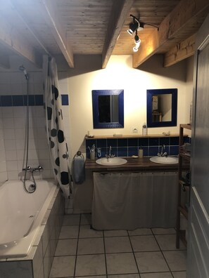 Ein Badezimmer mit einer Badewanne, zwei Waschbecken, einer Dusche und einem Deckenventilator.