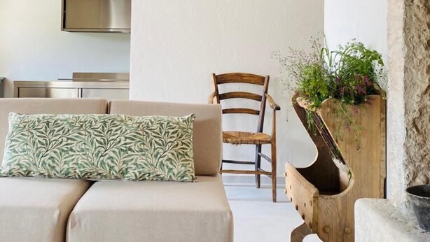 A cozy living area with a sofa, a wooden chair, and a unique planter. - Corte Massimago (Mezzane di Sotto)