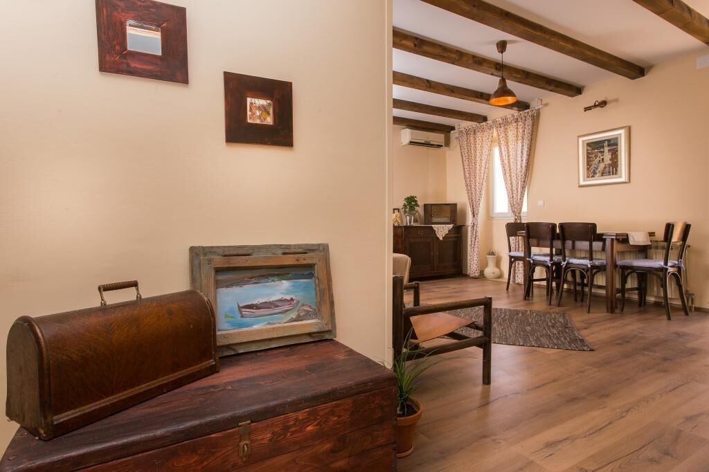 Un salon chaleureux avec un banc en bois, une radio ancienne et un tableau représentant un bateau accroché au mur.
