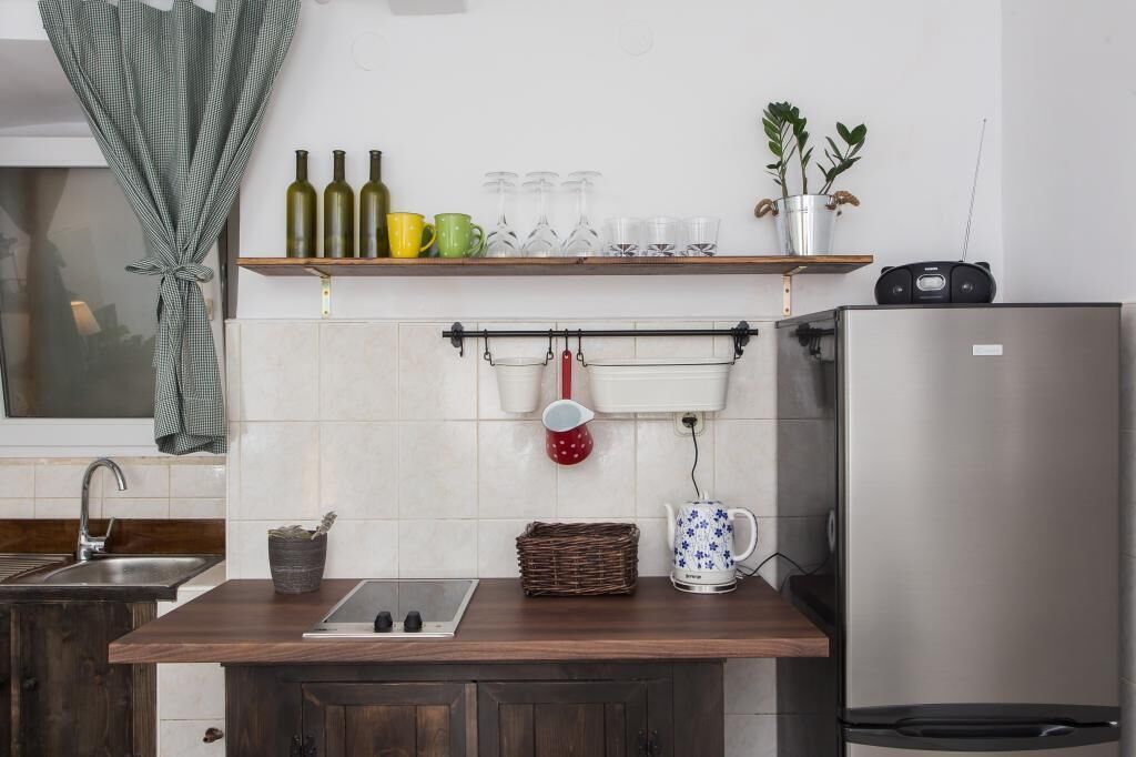 Eine moderne Küche mit einem Edelstahl-Kühlschrank, einer Holzarbeitsplatte, einem Spülbecken und einem Hängegestell mit Tassen und Weingläsern.