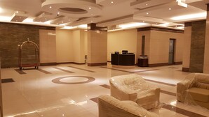 A spacious lobby with a reception desk, a waiting area with cushioned seating, and a decorative metal cart. - Magic Suite ALMahboula 2 (Mahboula)