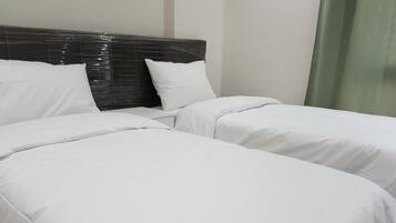 Habitación de hotel con dos camas individuales, cabecera oscura y ropa de cama blanca.