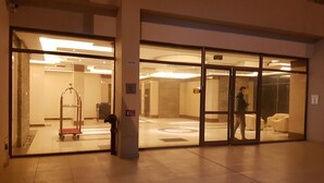 A hotel entrance with a reception desk, a glass door, and a tiled floor. - Magic Suite ALMahboula 2 (Mahboula)