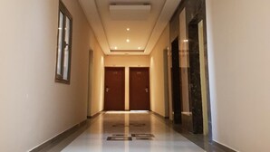 A hallway with a tiled floor, two doors at the end, and a ceiling with recessed lighting. - Magic Suite ALMahboula 2 (Mahboula)
