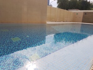 A swimming pool with a tiled floor and a wall with an exit sign.