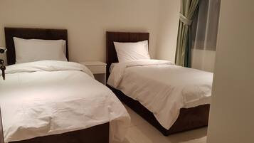 Una habitación de hotel con dos camas, una mesita de noche y una ventana con cortinas.