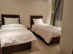 A hotel room with two beds, a nightstand, and a window with curtains.