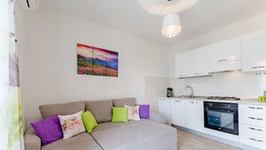 A modern living room with a beige sofa, a coffee machine, and a built-in oven. - Apartment Anamaris (Solin)