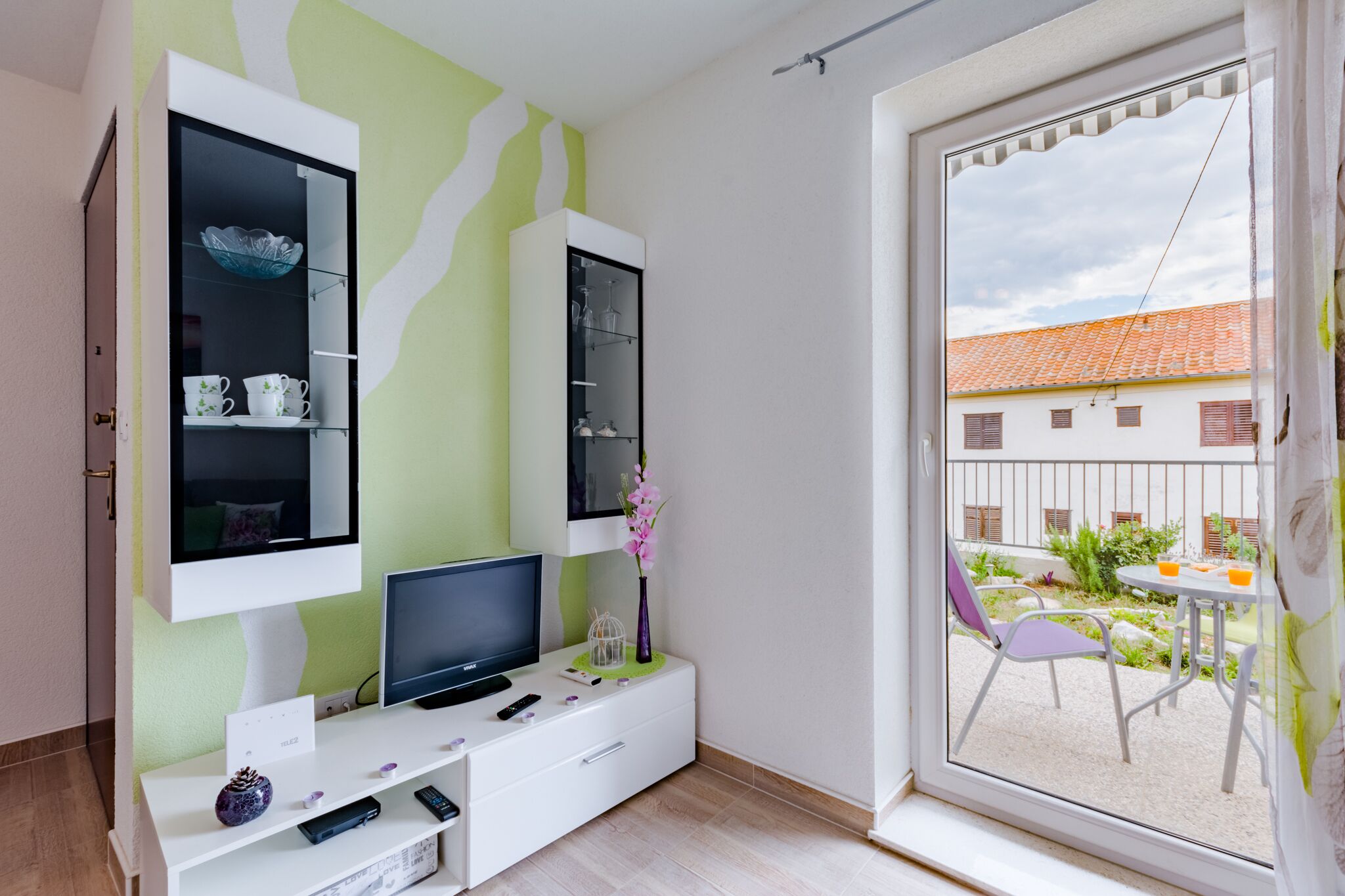 A modern living room with a TV, entertainment system, and a view of an outdoor patio.