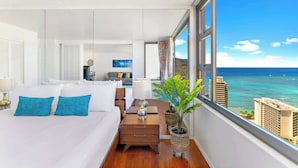 Habitación de hotel moderna con una cama grande, una mesita de noche, una lámpara, una planta en maceta y vistas al océano.
