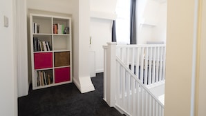 Ein Zimmer mit einem weißen Bücherregal, einem schwarzen Teppich und einem weißen Babybett.