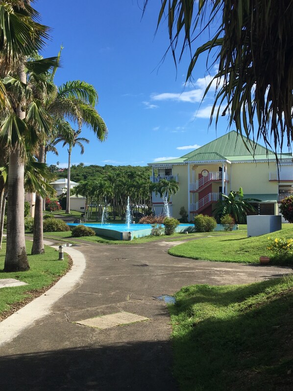 Um hotel com telhado verde, piscina e palmeiras.