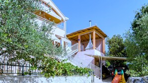 A children's play area with a slide, a covered playhouse, and a stone wall. - Apartments Donita (Dubrovacko Primorje)