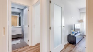 A hallway with a bathroom, a dark wood floor, and a white door. - Savory White Apartment, Wifi, AC !new! (Lisboa)