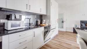 A modern kitchen with white cabinets, a microwave, a toaster, and a dishwasher. - Savory White Apartment, Wifi, AC !new! (Lisboa)