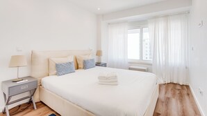 A neatly arranged hotel room with a large bed, bedside tables, and a window with curtains. - Savory White Apartment, Wifi, AC !new! (Lisboa)