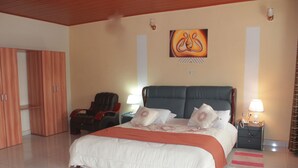 A hotel room with a large bed, a massage chair, a wardrobe, and a painting on the wall. - Delta Resort Hotel (Bwishyura)