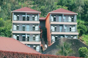 A multi-story building with balconies, surrounded by lush greenery. - Delta Resort Hotel (Bwishyura)