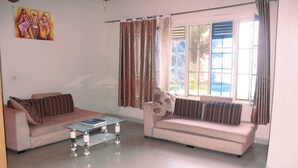 A living room with two sofas, a glass coffee table, and a window with curtains. - Delta Resort Hotel (Bwishyura)