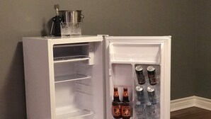Un réfrigérateur blanc, dont la porte est ouverte, laissant apparaître des étagères remplies de bouteilles et de boîtes de conserve.
