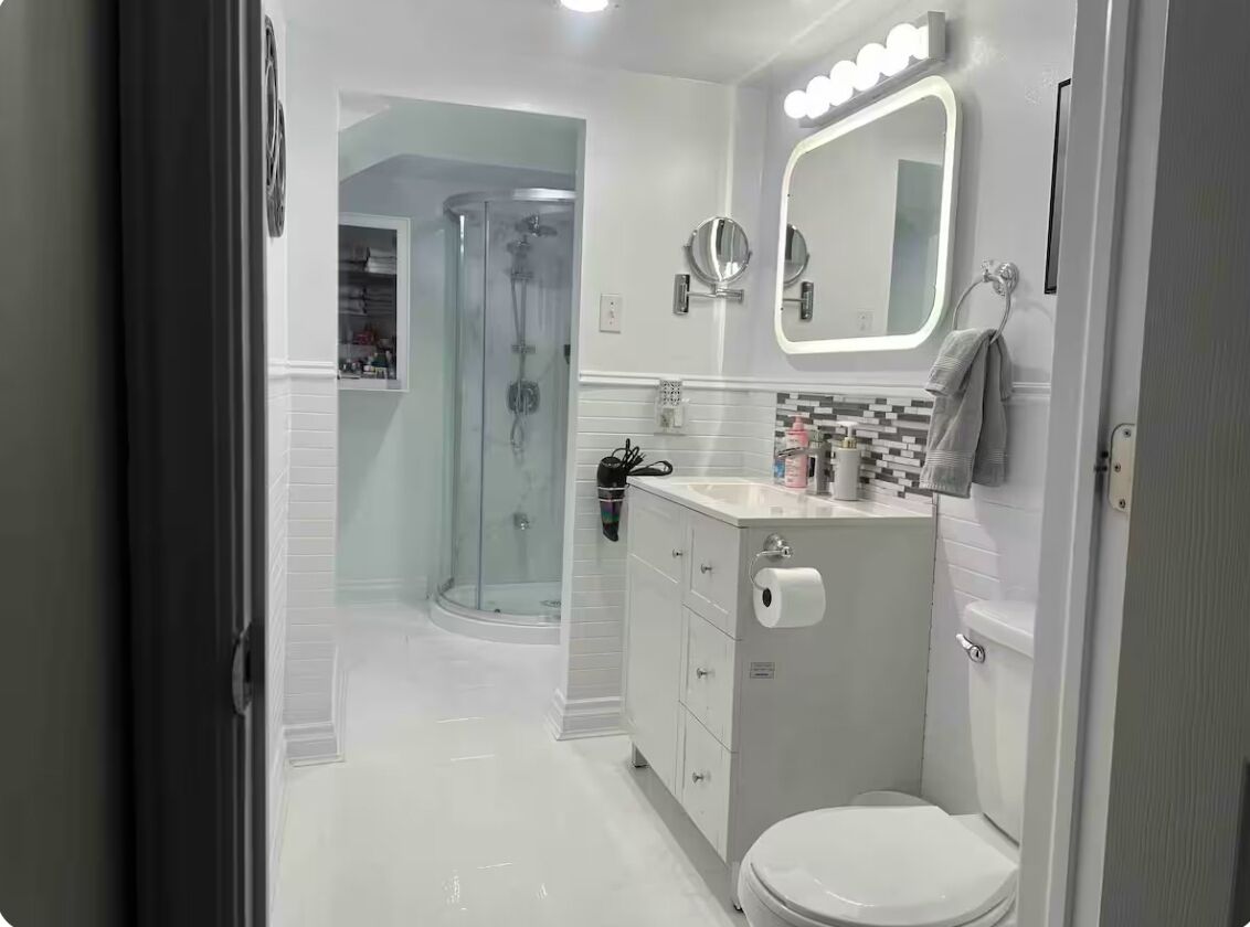 A modern bathroom with a glass shower enclosure, a vanity with a mirror, and a toilet.