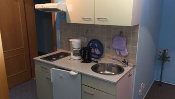 Een koffiezetapparaat/waterkoker, een koelkast, een oven, een kookplaat