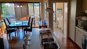 A modern kitchen with a dining area, a washing machine, and a view of the backyard. - Modern Melville Plaza Townhouse close to Swan River and Port beach. (Palmyra)