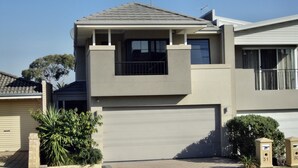 A modern two-story house with a garage, a balcony, and a small garden area. - Modern Melville Plaza Townhouse close to Swan River and Port beach. (Palmyra)