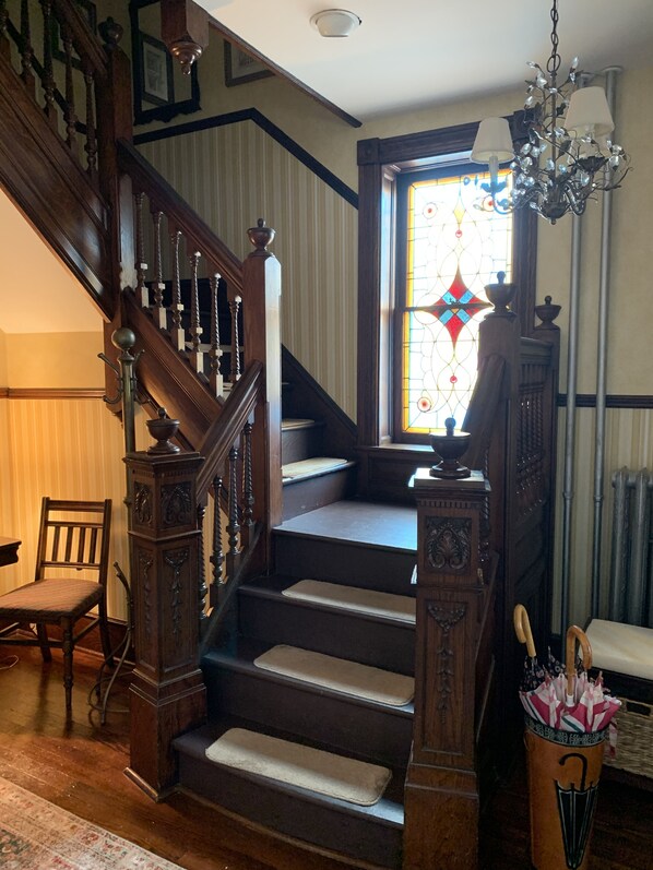A staircase with wooden railings and a stained glass window at the top. - Beautiful 6 BR House in center of  Historic District 1 Block to Beach   (Cape May)