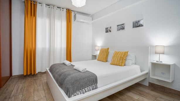 Une chambre d’hôtel moderne avec un grand lit, deux tables de chevet et un climatiseur fixé au mur.