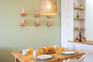 Una mesa de desayuno con platos, vasos y pastelería, una pared de madera con piezas de ajedrez y una lámpara colgante.