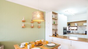Een moderne keuken met witte kasten, een houten aanrechtblad en een hanglamp.